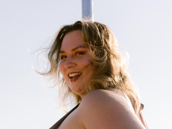 Rose Beach laughing over her shoulder on the beach, the pole behind her